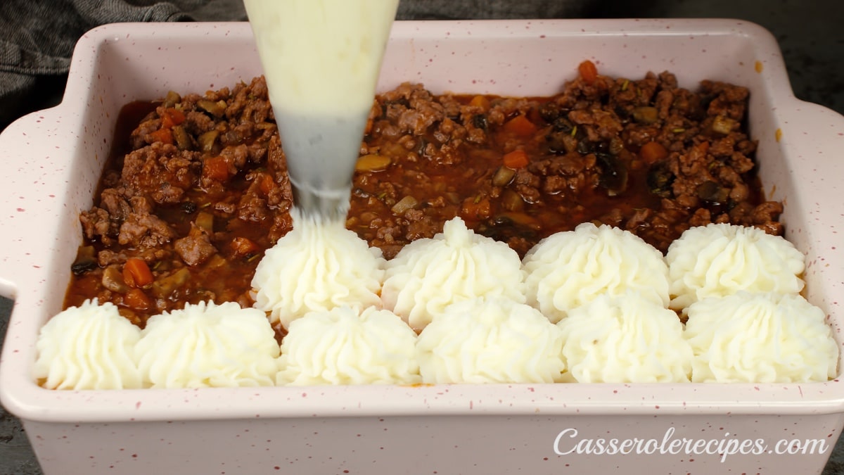piping mashed potatoes onto beef mixture
