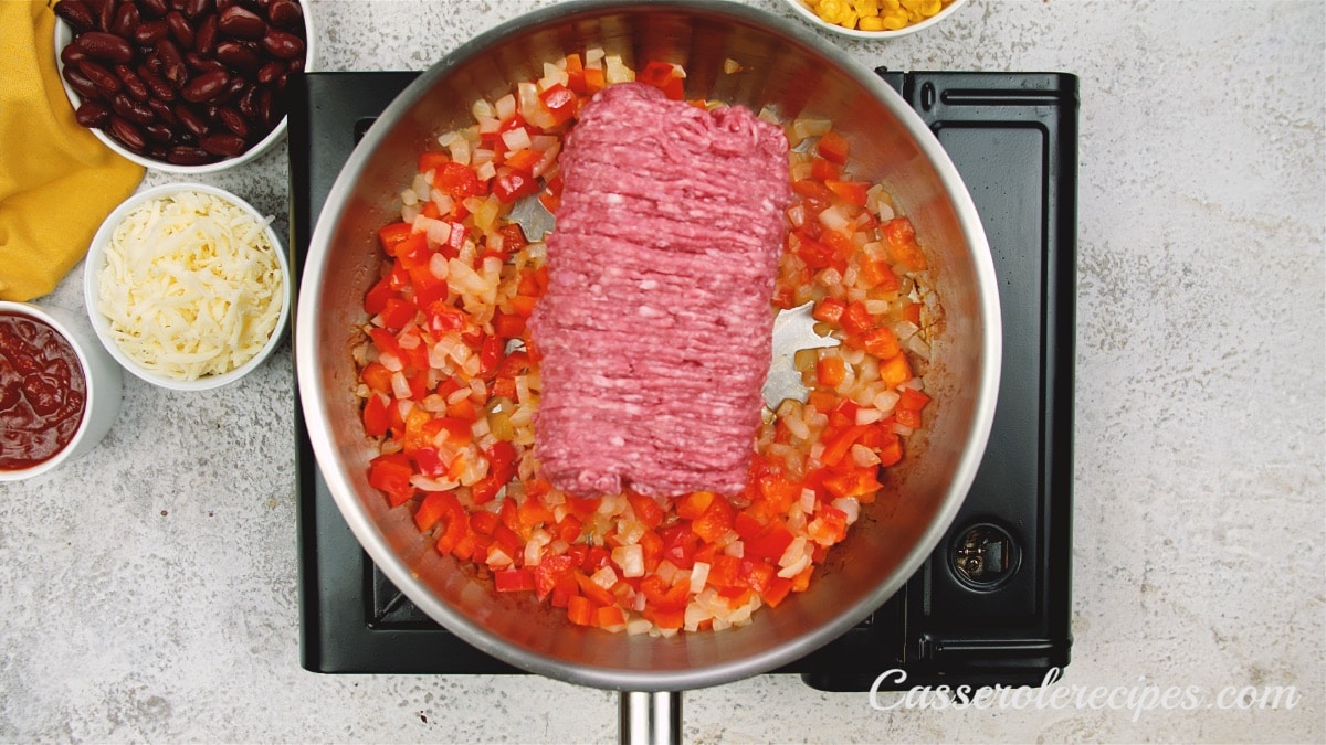 raw beef on vegetables in pan
