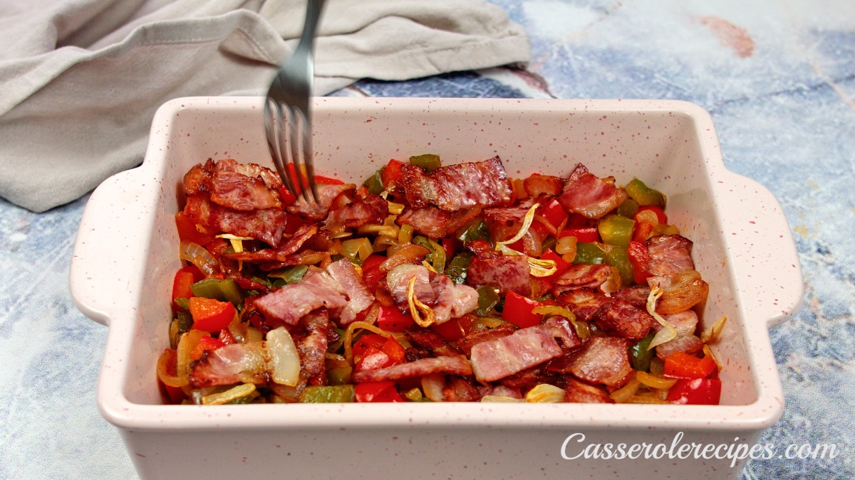 mixing vegetables and bacon in baking dish with fork