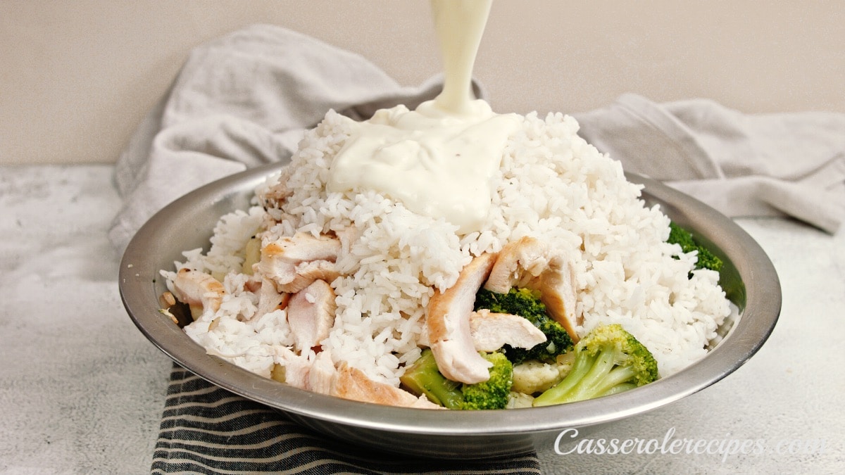 pouring cheese sauce over chicken and vegetables