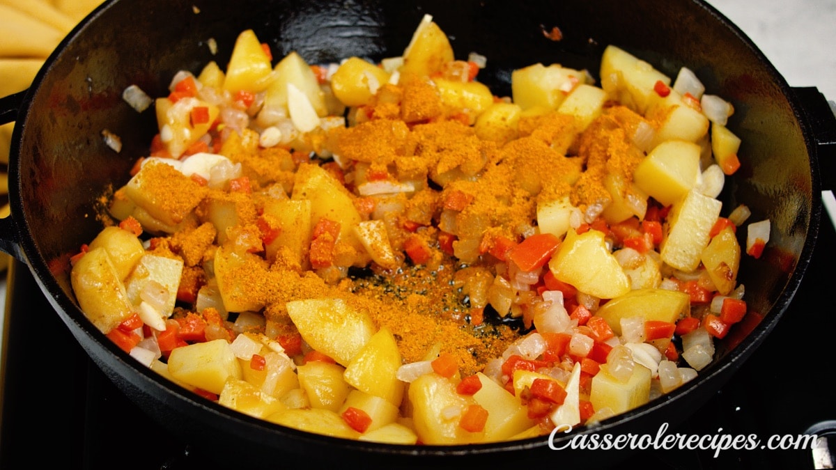 curry added to potatoes in pan