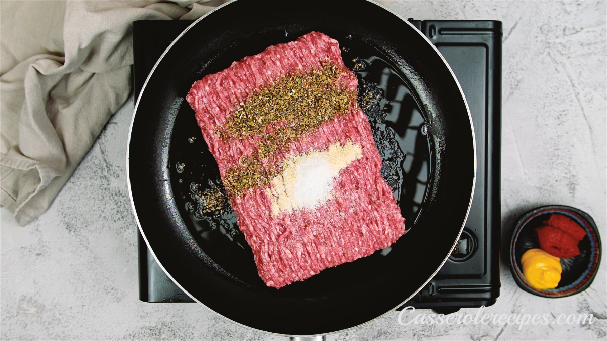 seasonings topping ground beef in a saute pan