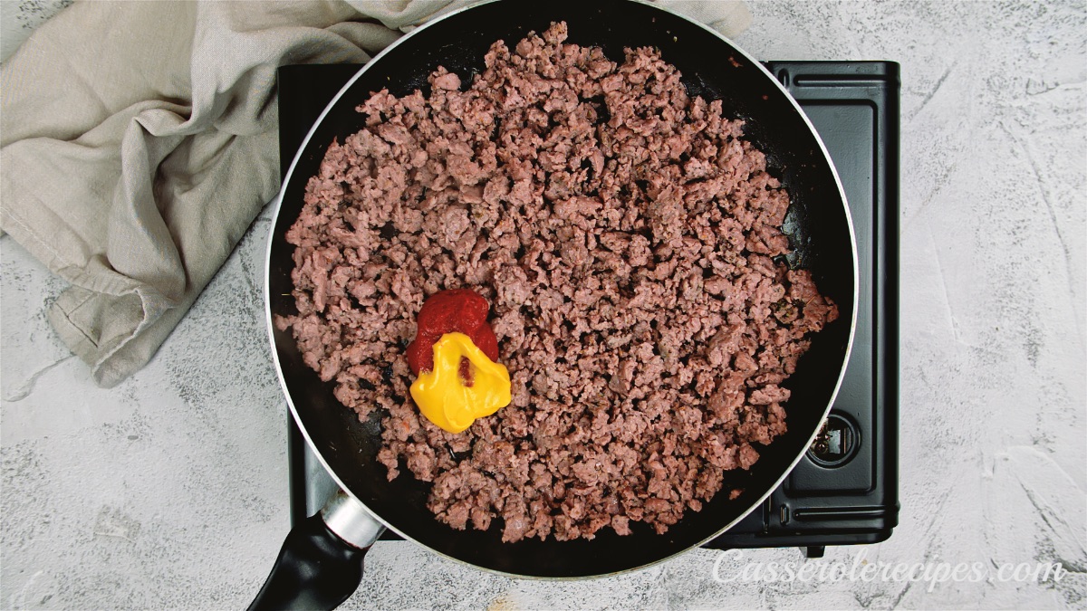 ketchup and mustard on top of ground beef in pan