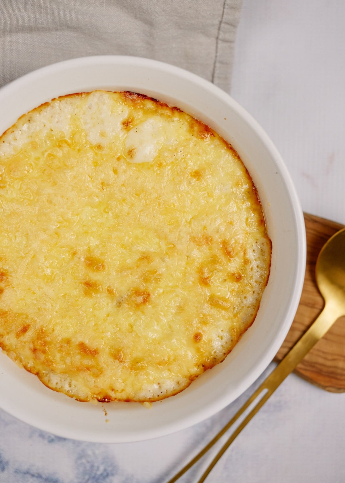 baked macaroni casserole in a white baking dish on a wood board