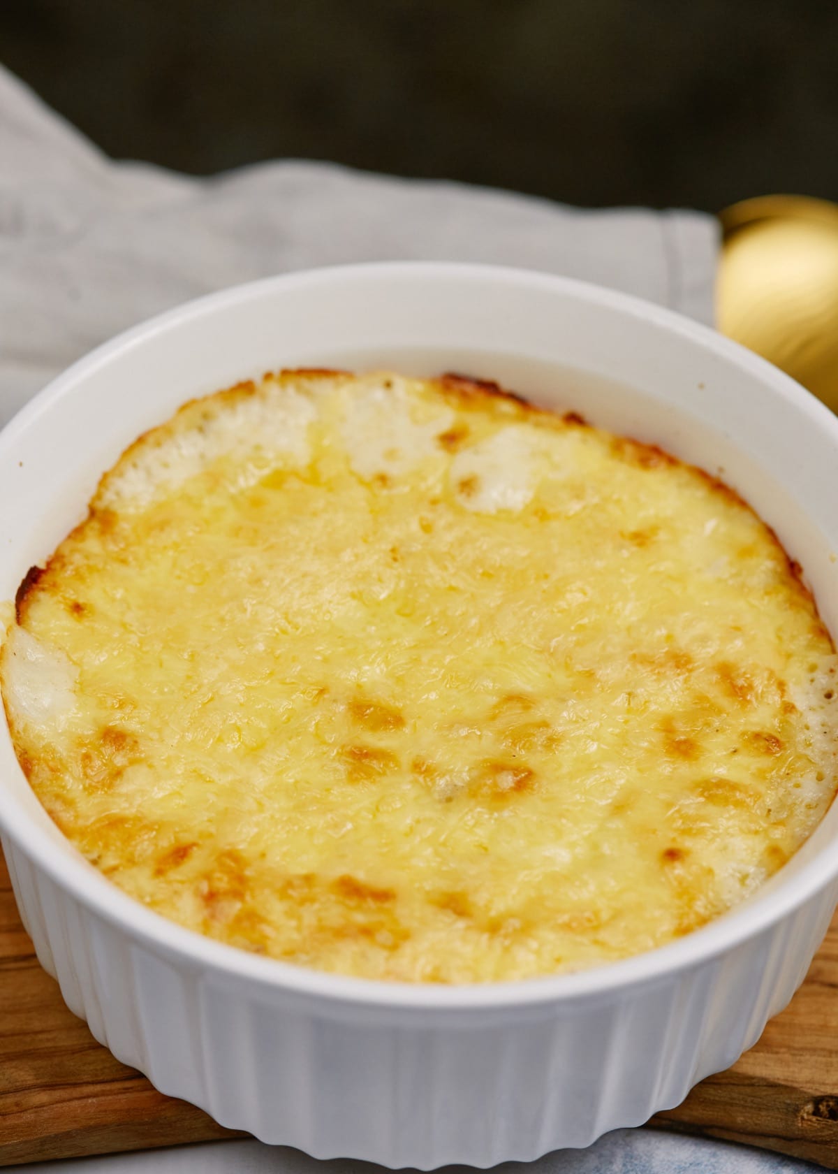 baked macaroni and cheese in round white baking dish on cutting board
