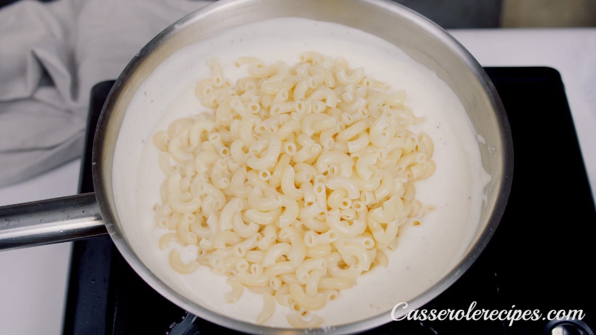 macaroni atop the cheese sauce in a pot