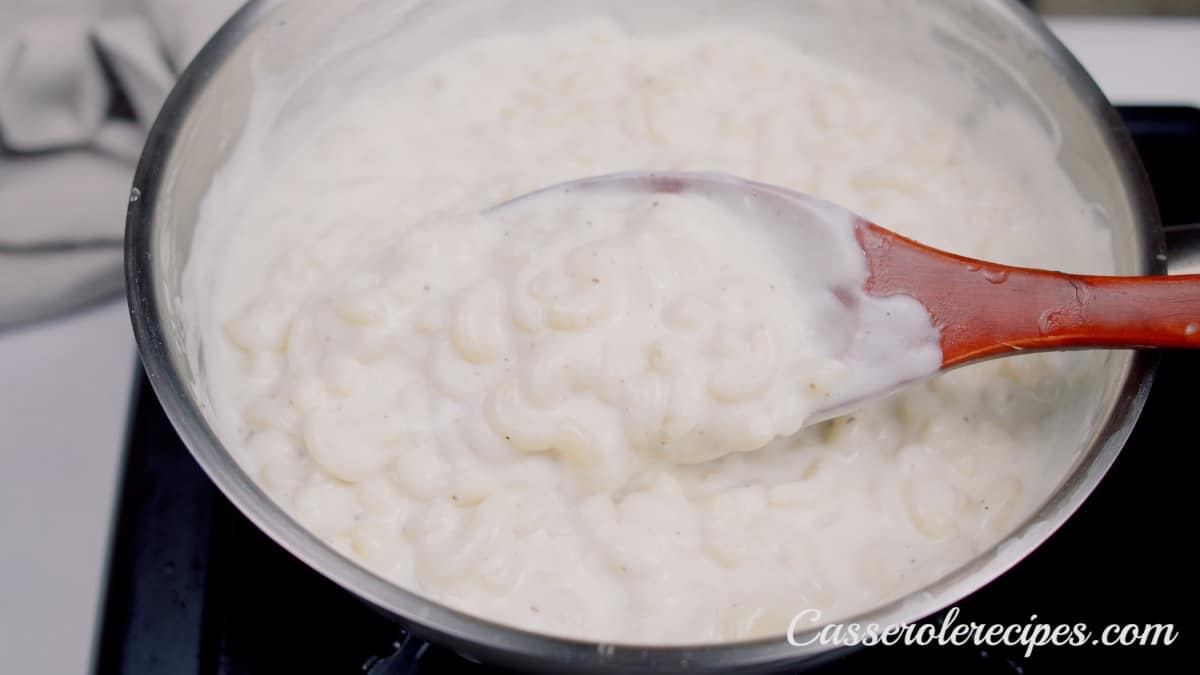 stirring creamy macaroni with a wooden spoon