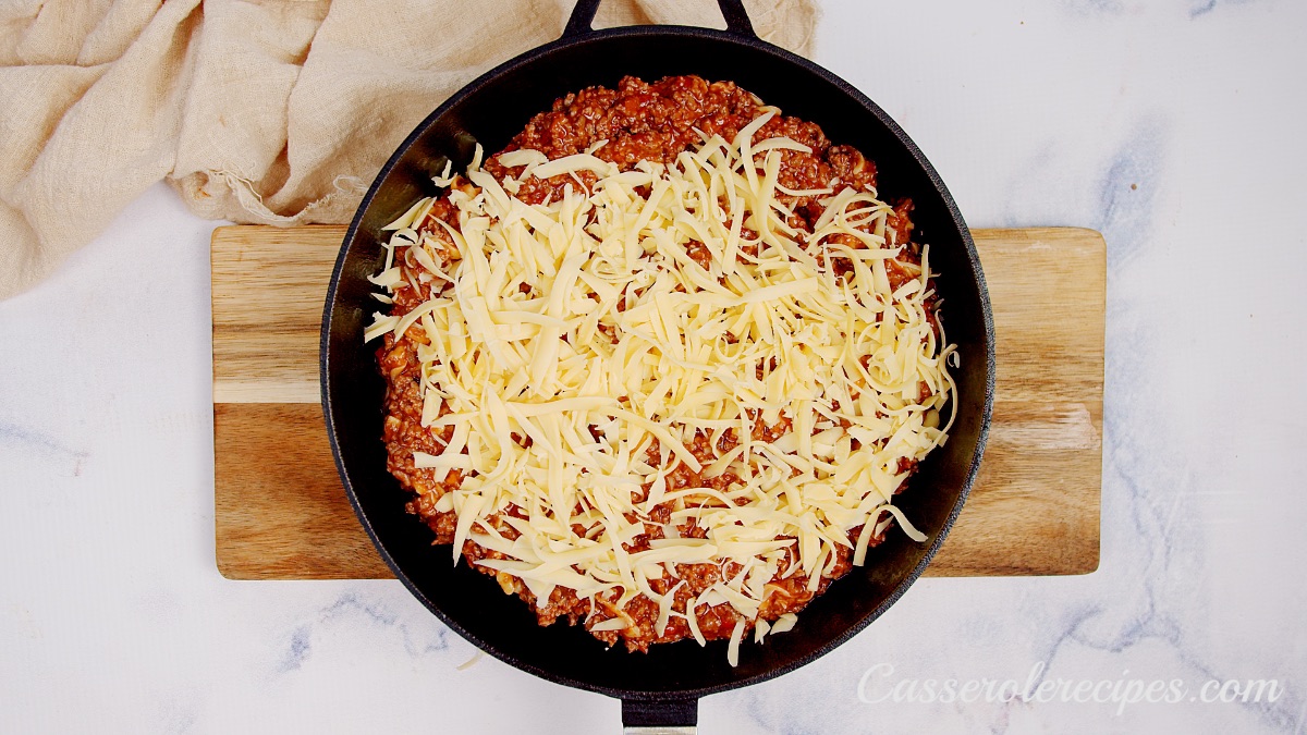 shredded cheese on top of beef mixture in cast iron pan
