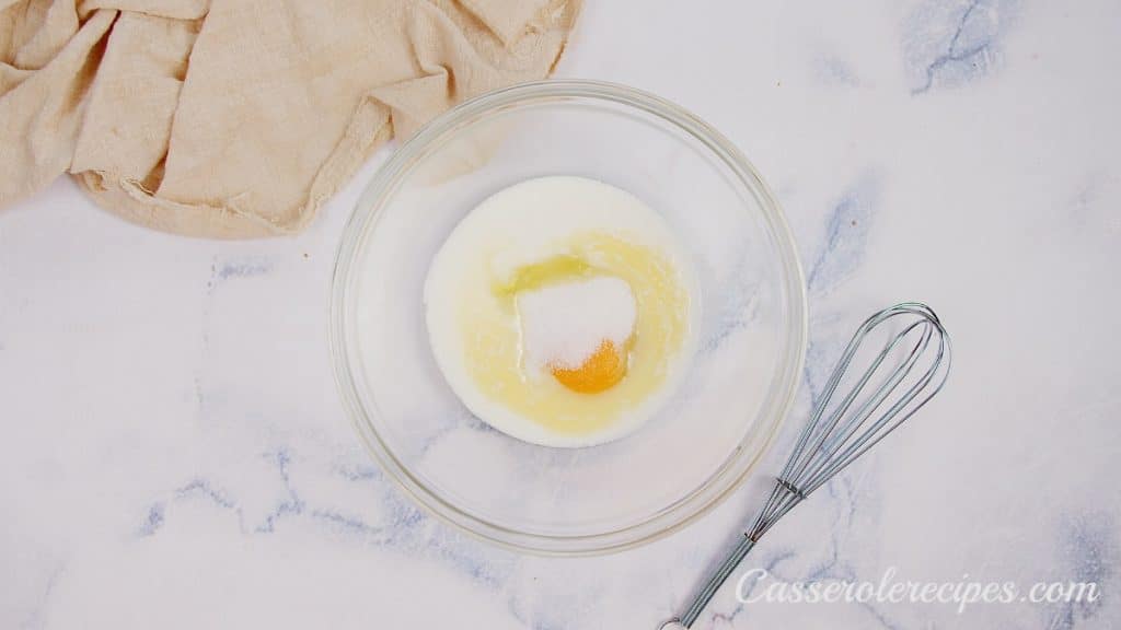 melted butter, egg, and buttermilk in a clear glass bowl on a white surface
