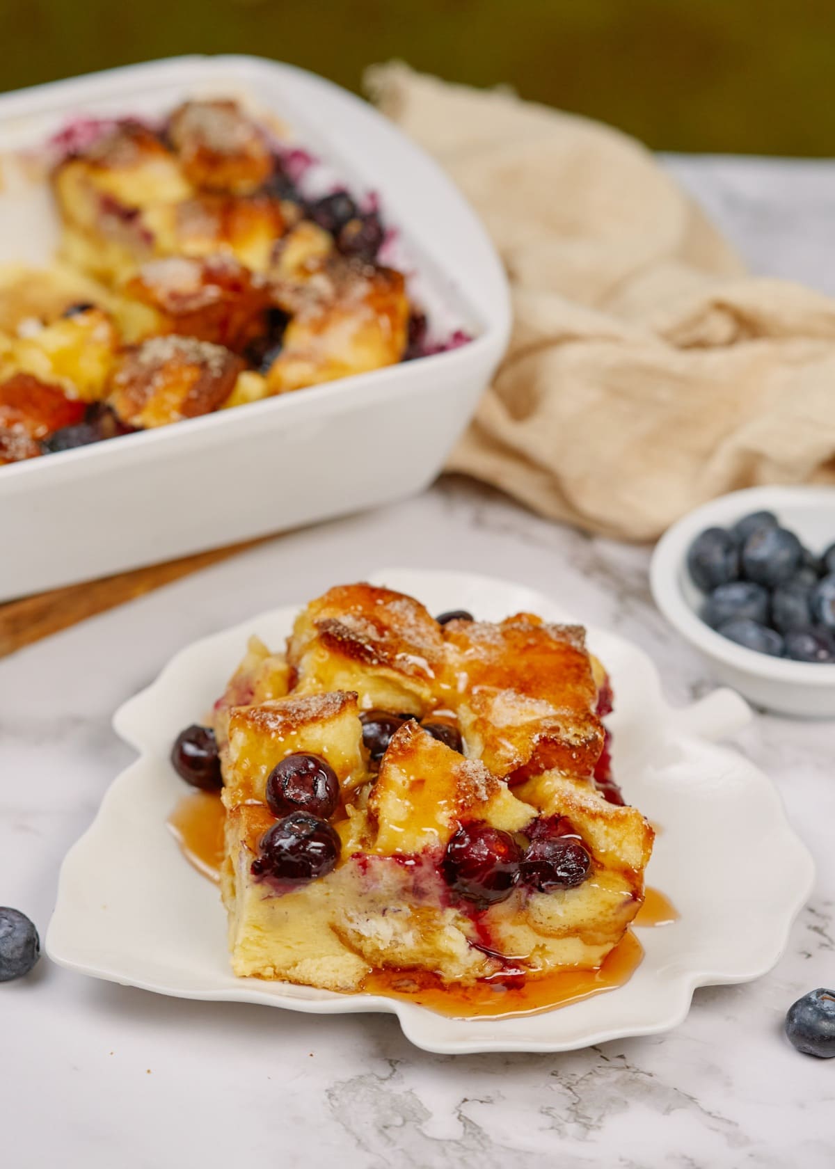 a slice of baked blueberry french toast casserole on a white plate