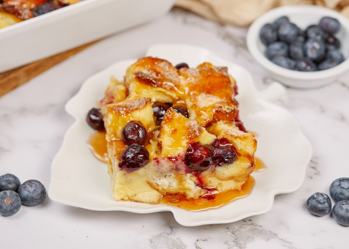 a slice of baked blueberry french toast casserole on a white plate