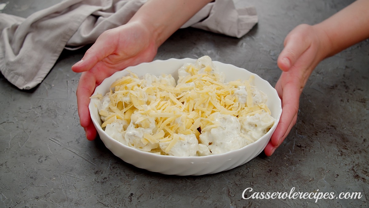 two hands holding a baking dish with cauliflower