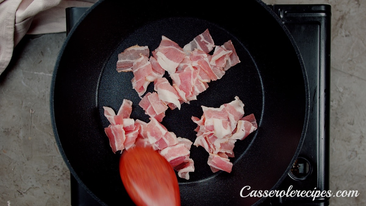 stirring raw chopped bacon in a saute pan with a wooden spoon