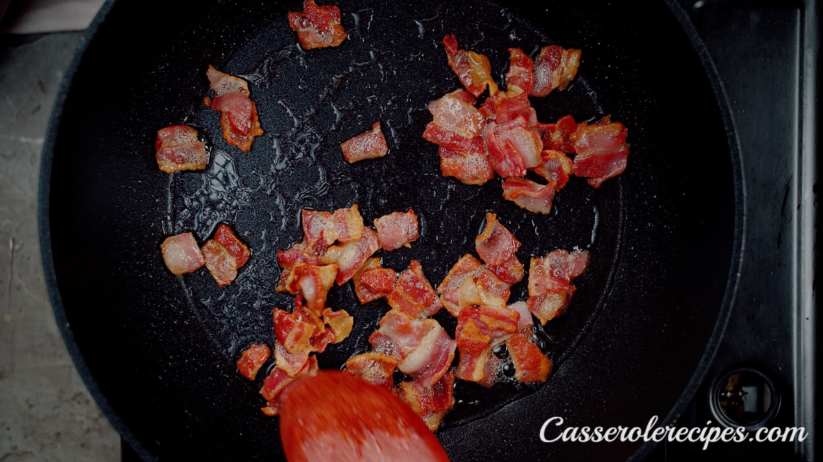 stirring cooked chopped bacon in a saute pan with a wooden spoon