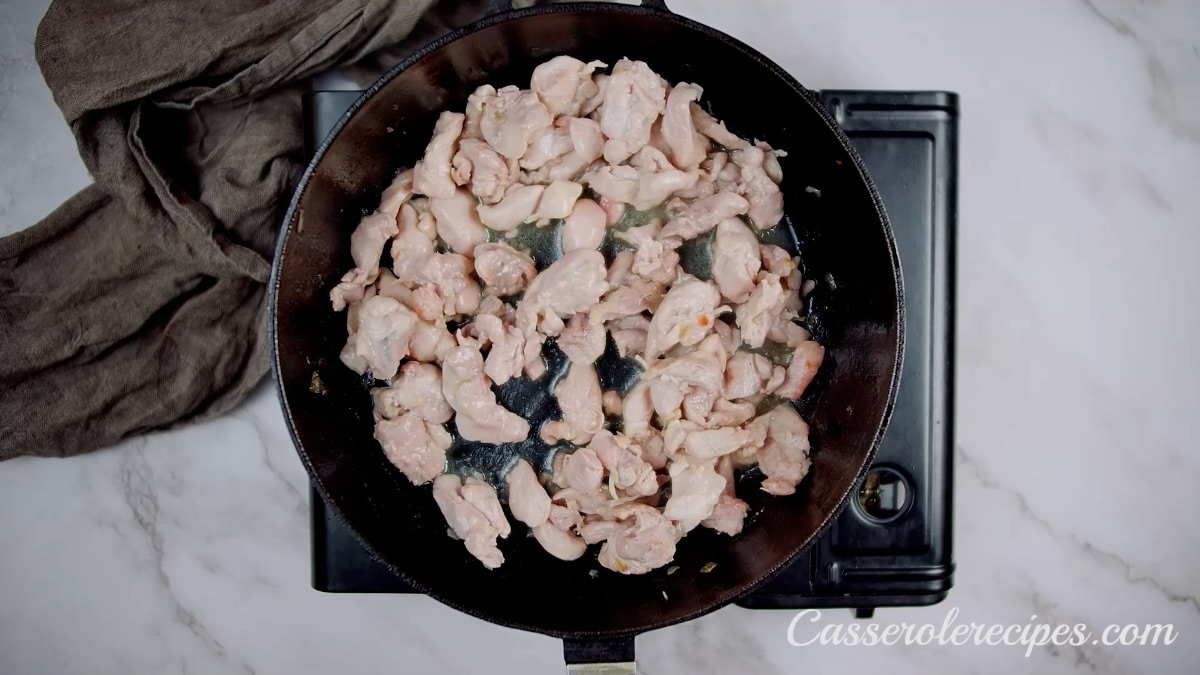 cooking chopped chicken in a cast iron pan