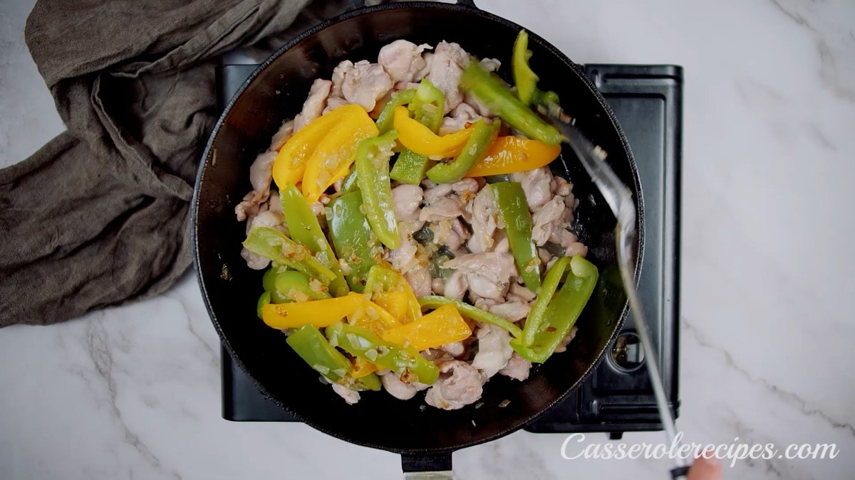 cooking peppers, onions, and chicken in pan