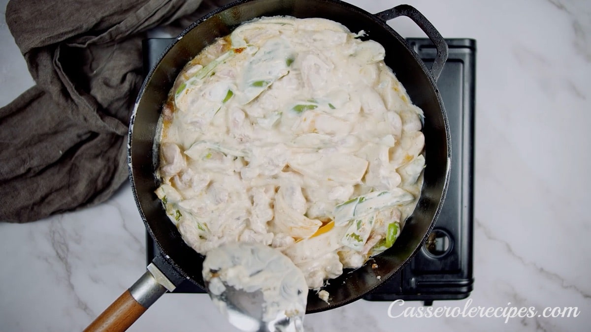 spreading chicken fajita casserole in pan with a spoon