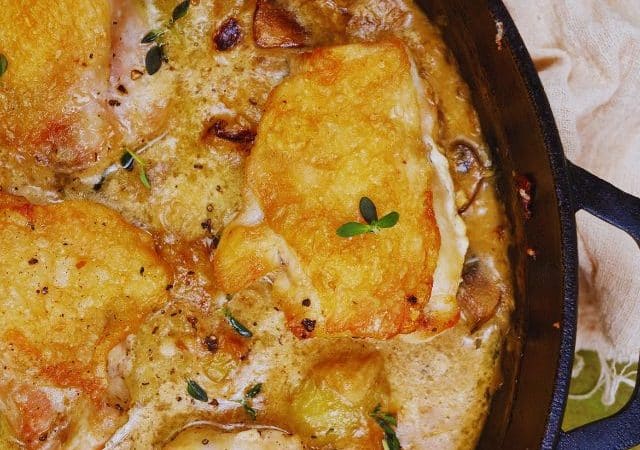 cast iron skillet of chciken and mushrooms in sauce