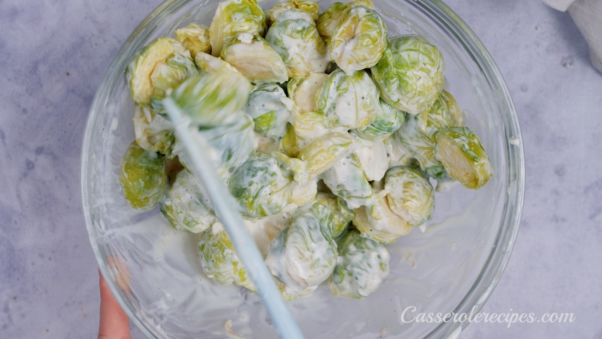 stirring brussel sprouts with cream with a blue spatula