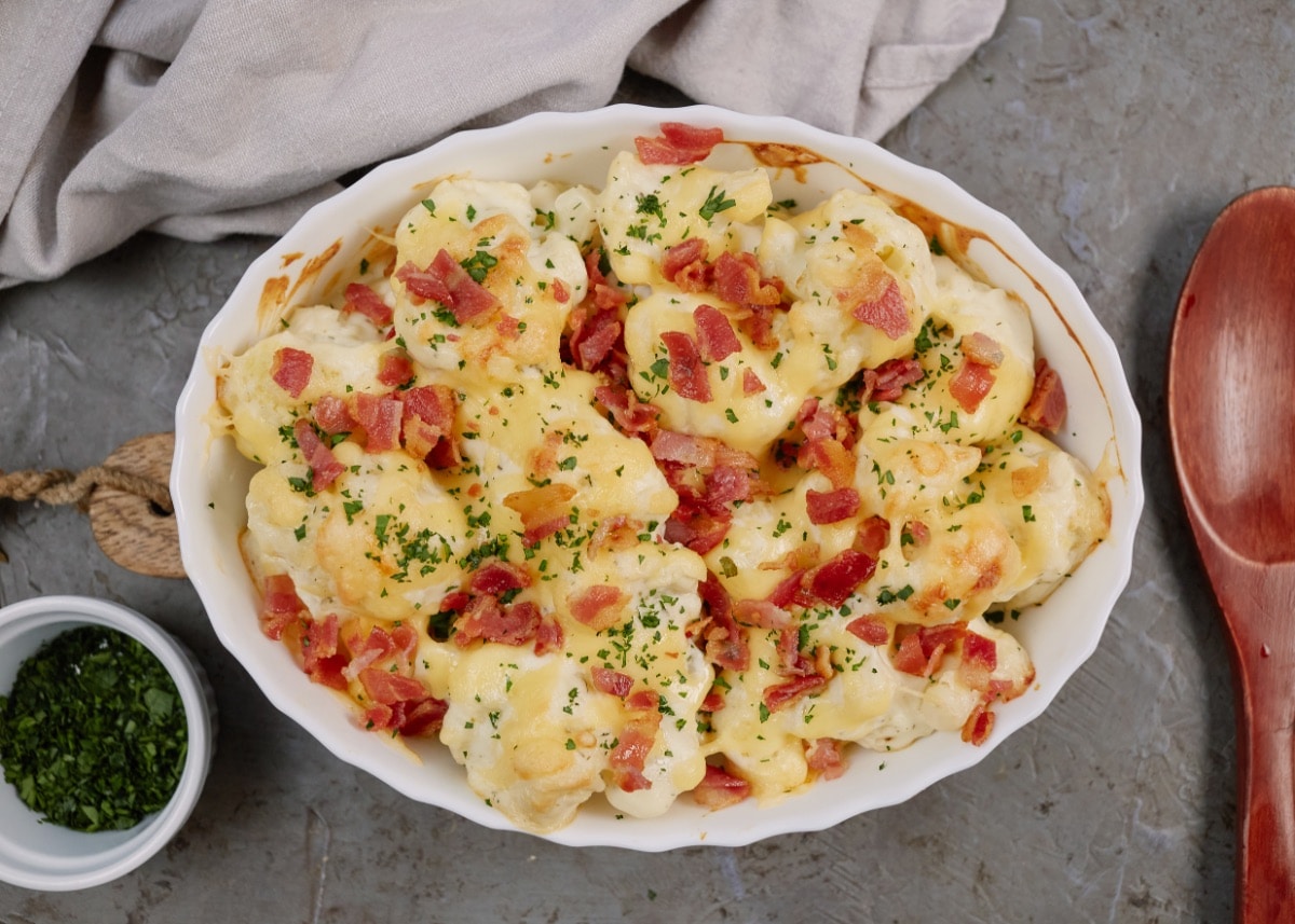 baked loaded cauliflower casserole topped with chopped bacon in casserole dish