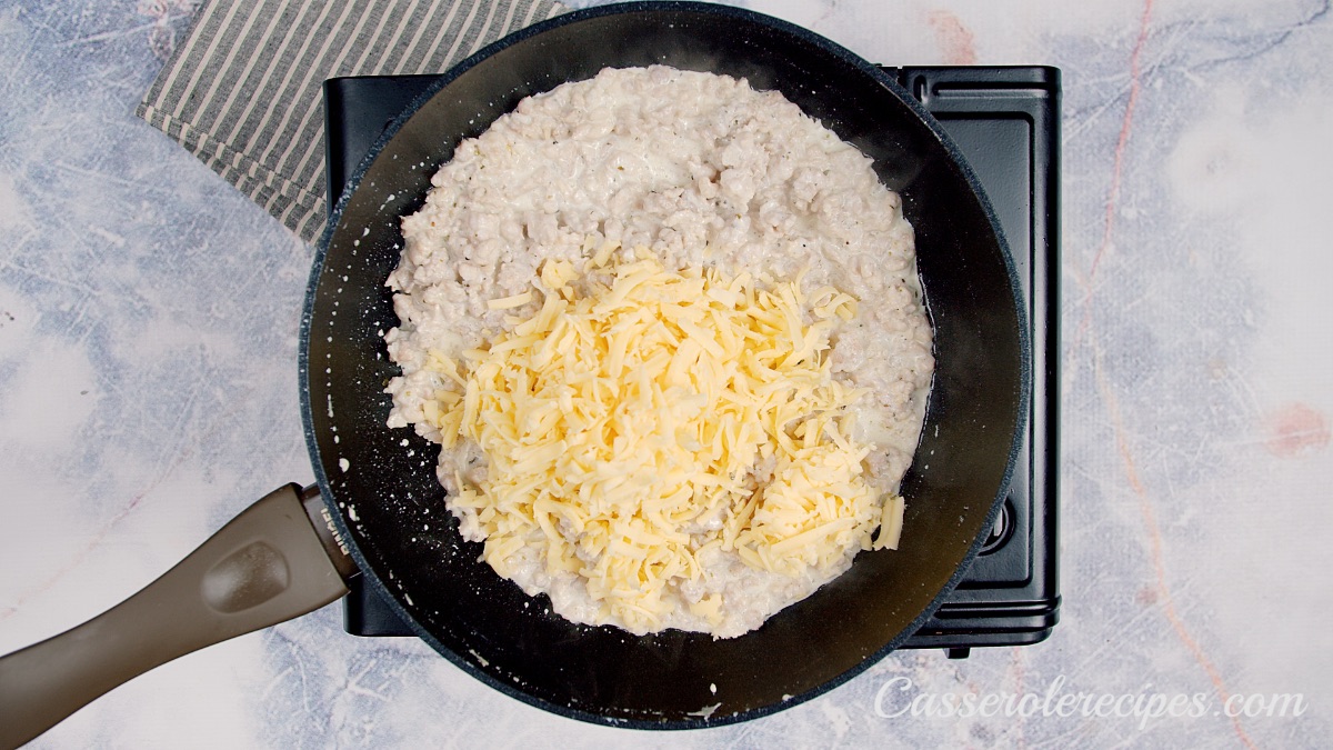 shredded cheese on top of ground chicken in pan