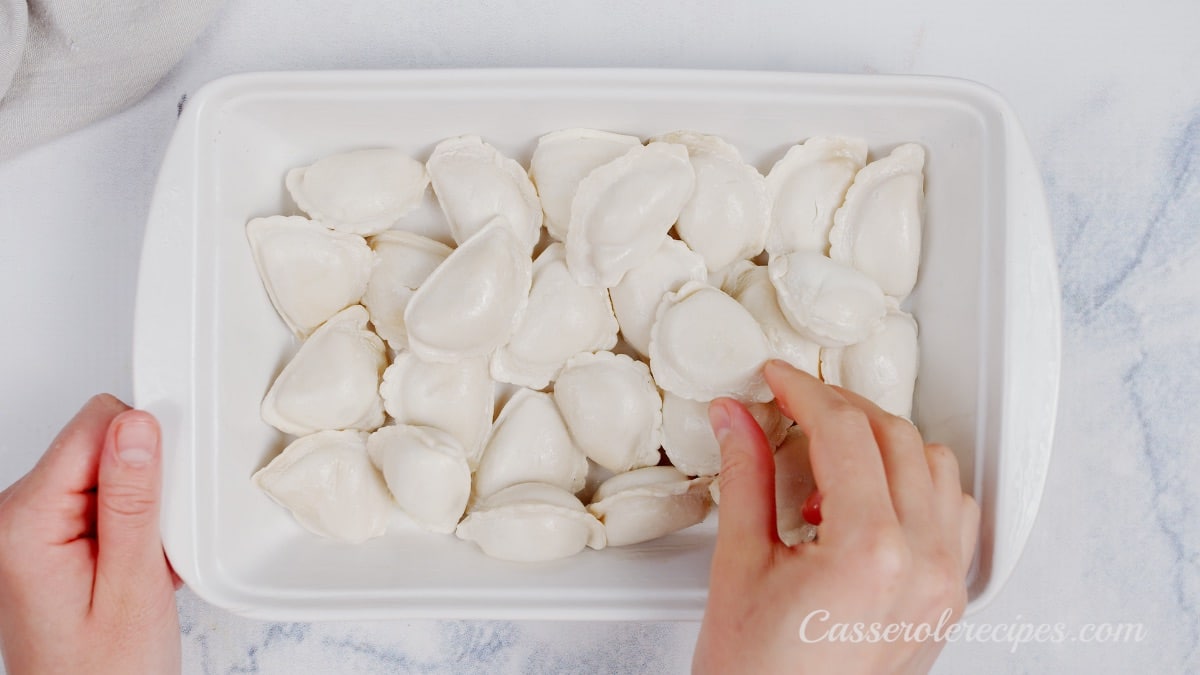 laying pierogis in a glass baking dish