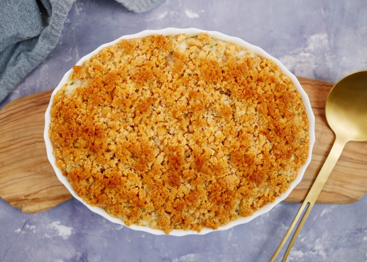 baked creamy ritz casserole in a baking dish on a wooden board