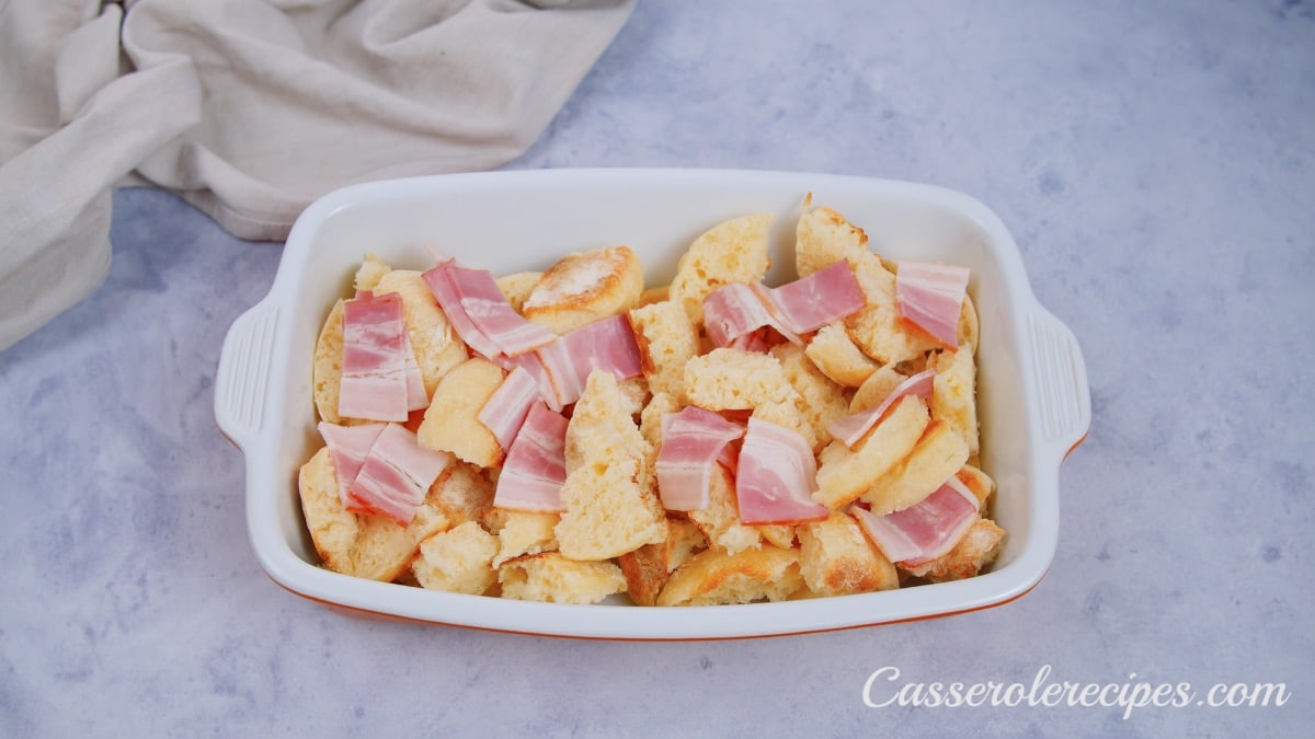 a baking dish filled with torn bread and chopped bacon