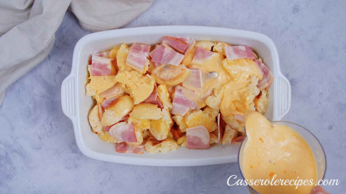 pouring egg mixture over casserole