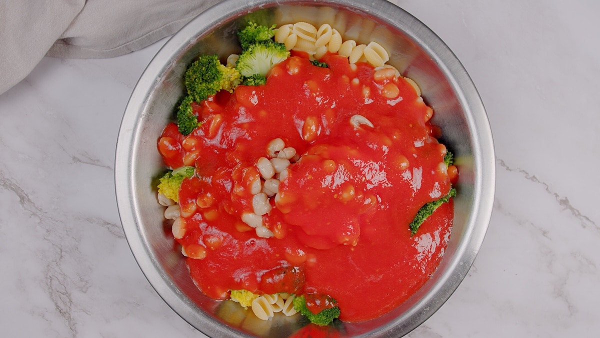 tomato sauce poured over bowl with broccoli and gnocchi