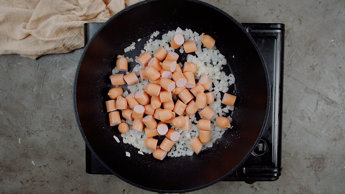 chopped hot dogs in pan with onions