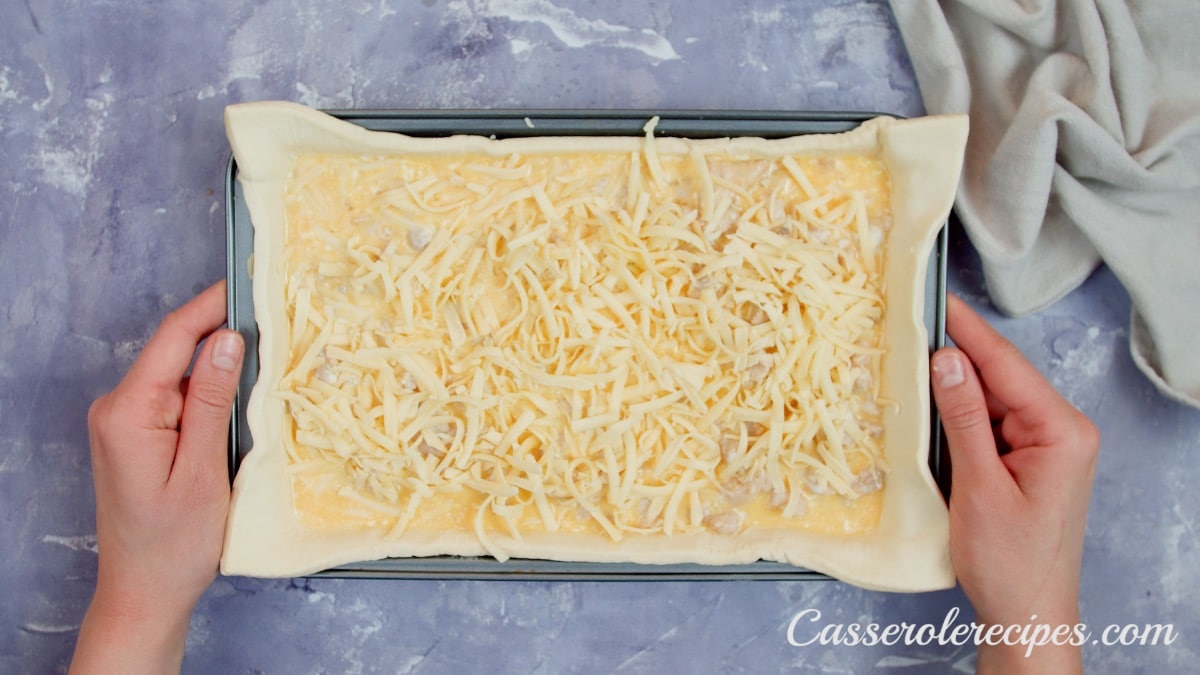 two hands holding baking dish with cheese on top