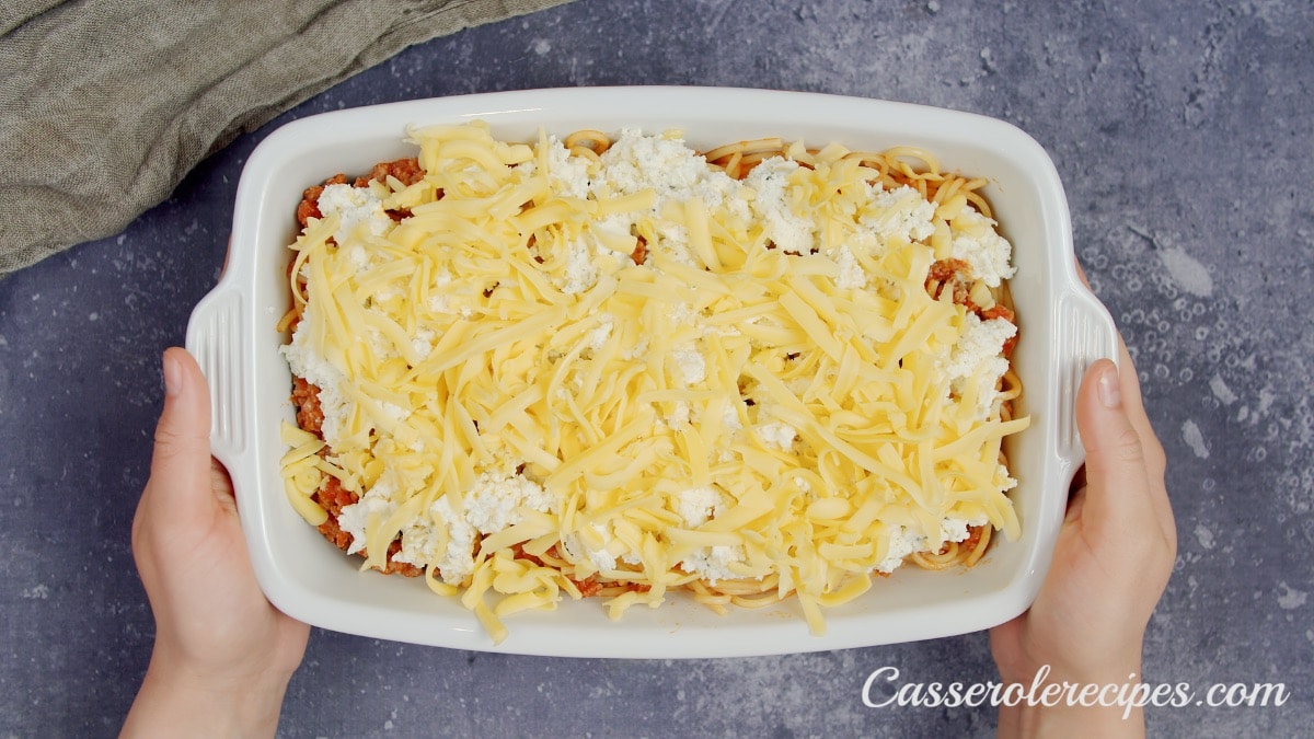 two hands holding baking dish of casserole