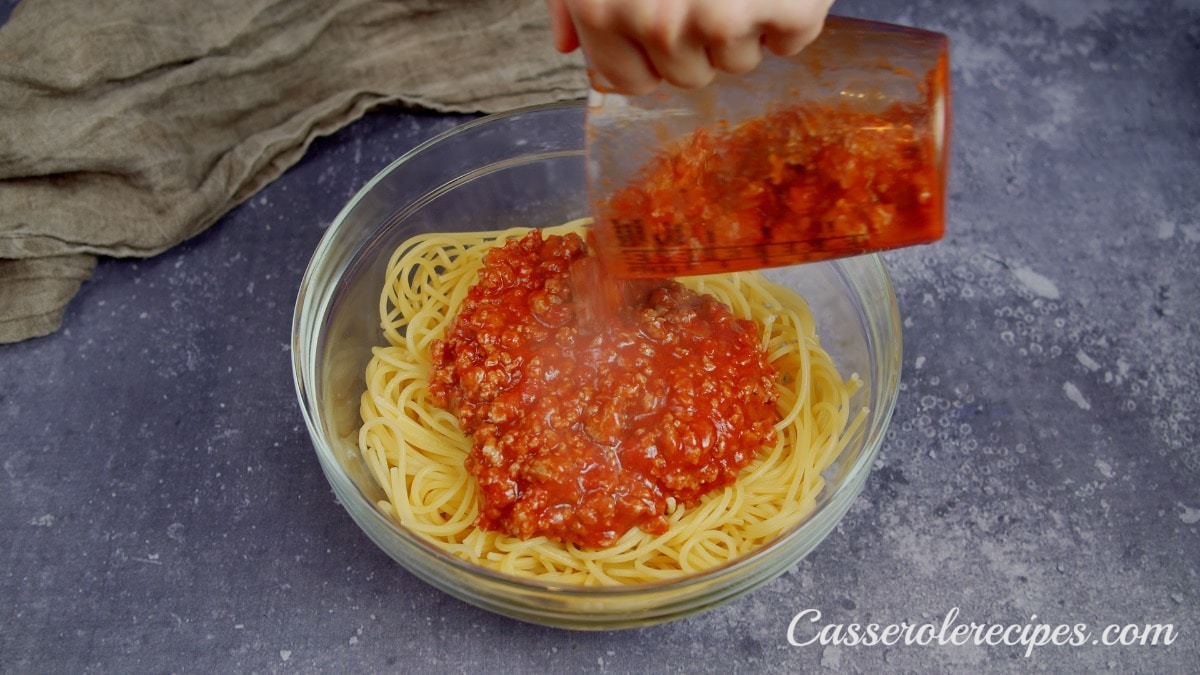 pouring sauce over cooked spaghetti