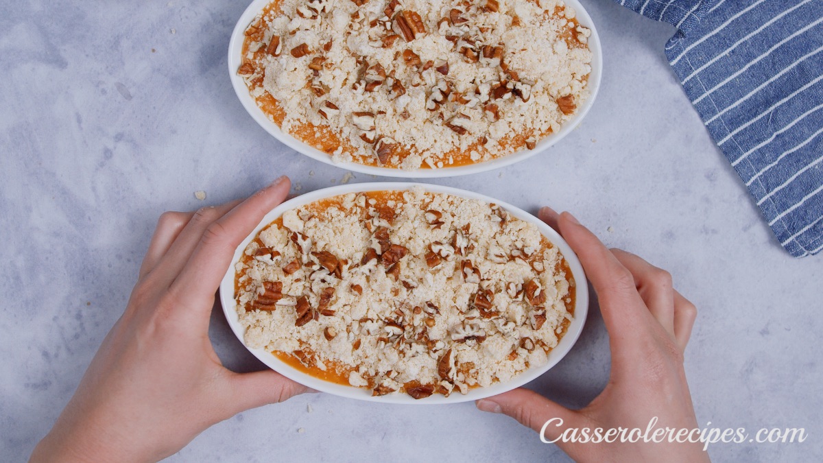 two hand holding one white baking dish of potato casserole