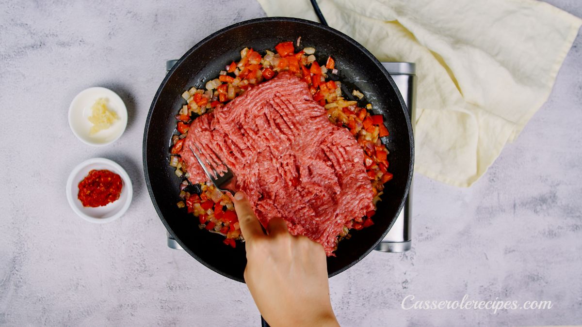 fork mashing ground beef in skillet