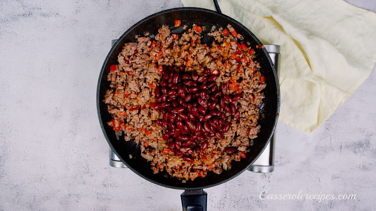 kidney beans on top of cooked ground beef in black skillet