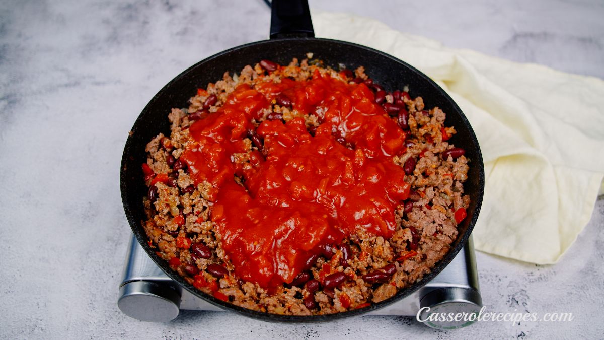 tomato sauce on top of ground meat in skillet