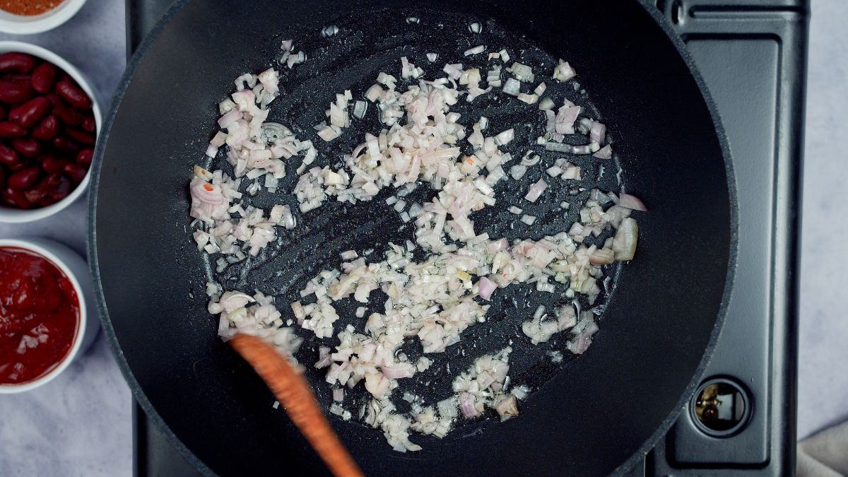 wooden spoon stirring onions in black skillet