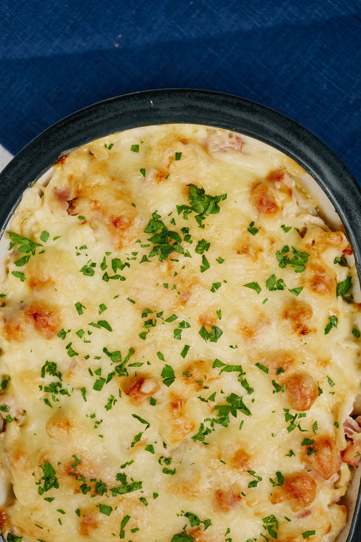 close up image of top of casserole showing browned cheese and parsley