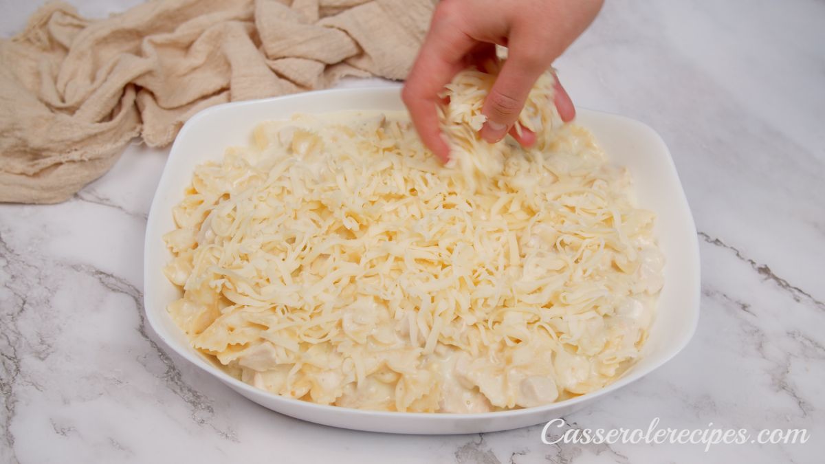 hand spreading shredded cheese on top of casserole