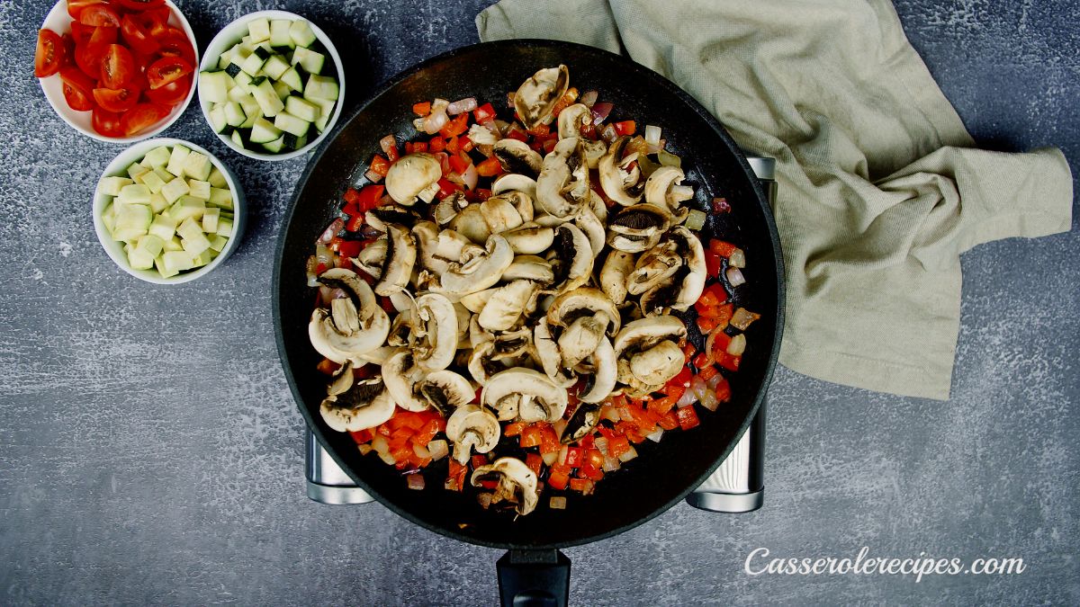 mushrooms on top of cooked peppers in skillet sitting on hot plate on blue table