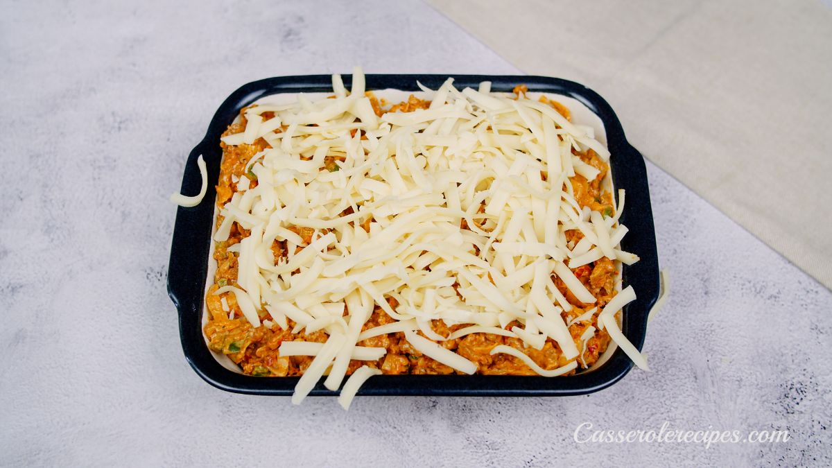 keto taco casserole in rectangular baking dish topped with white cheese before baking