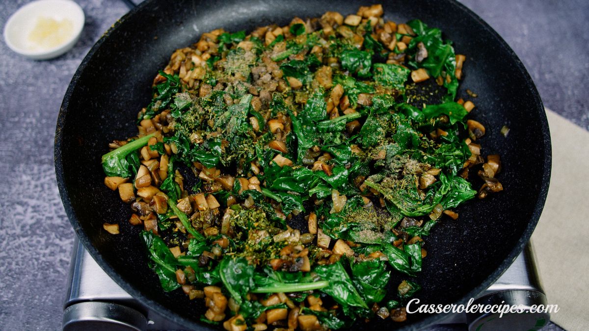 cooked spinach and mushrooms in black skillet