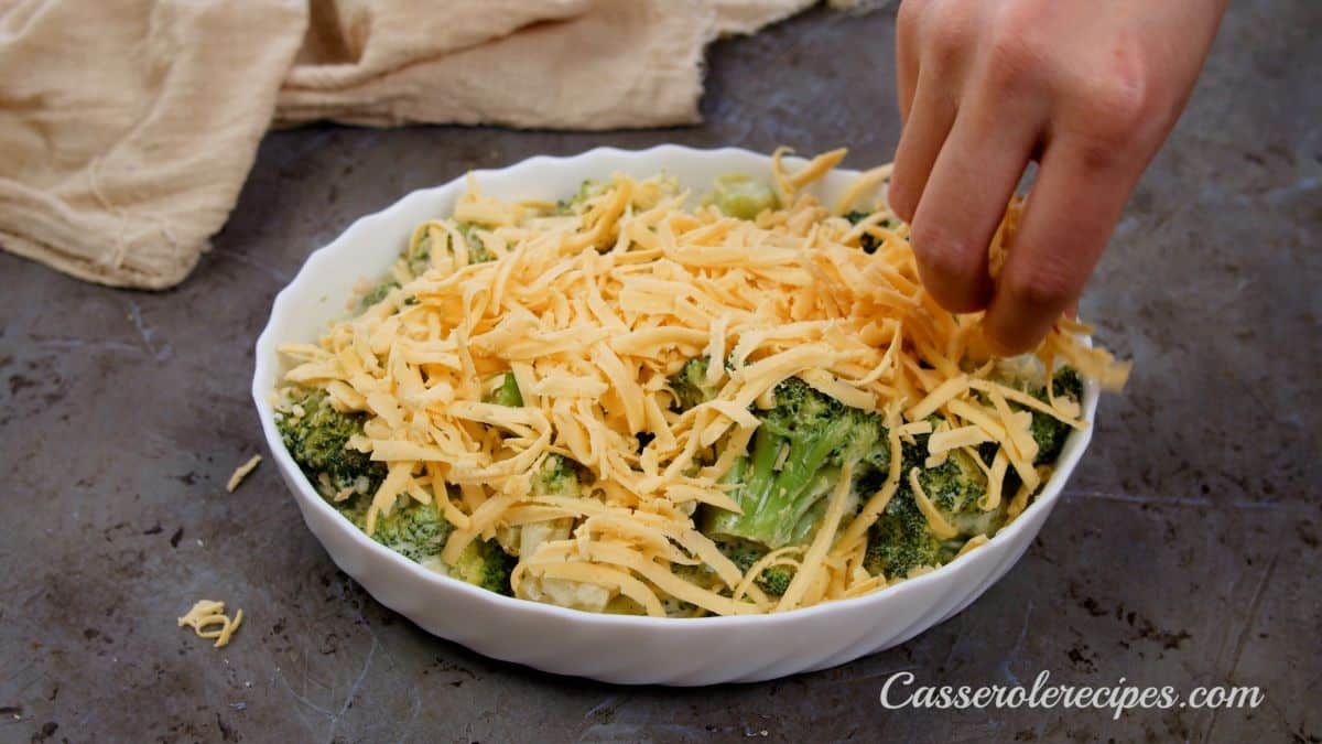 hand putting cheese over top of broccoli