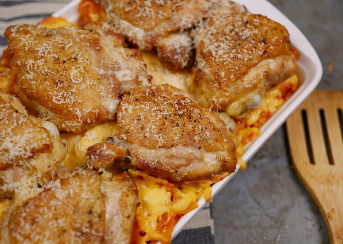 chicken thighs on top of pasta in white baking dish