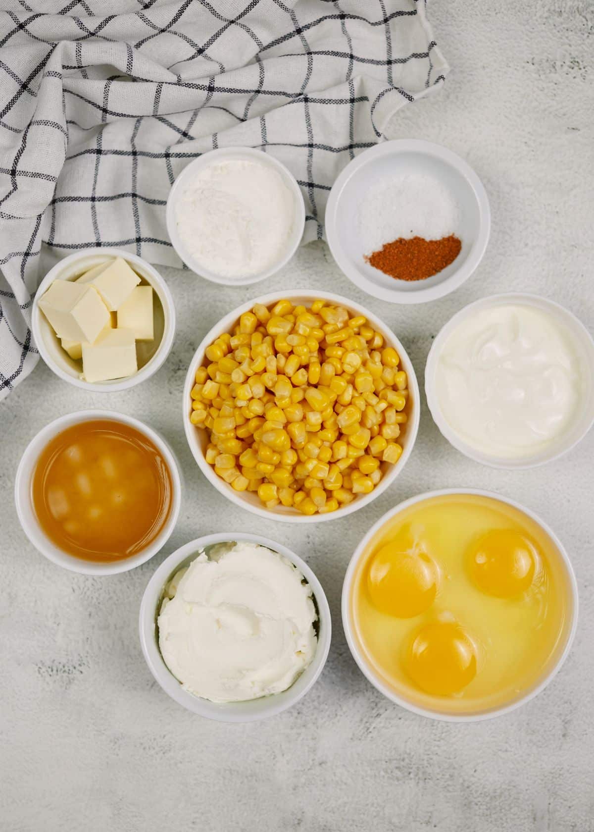 round white ramekins filled with ingredients for corn pudding casserole