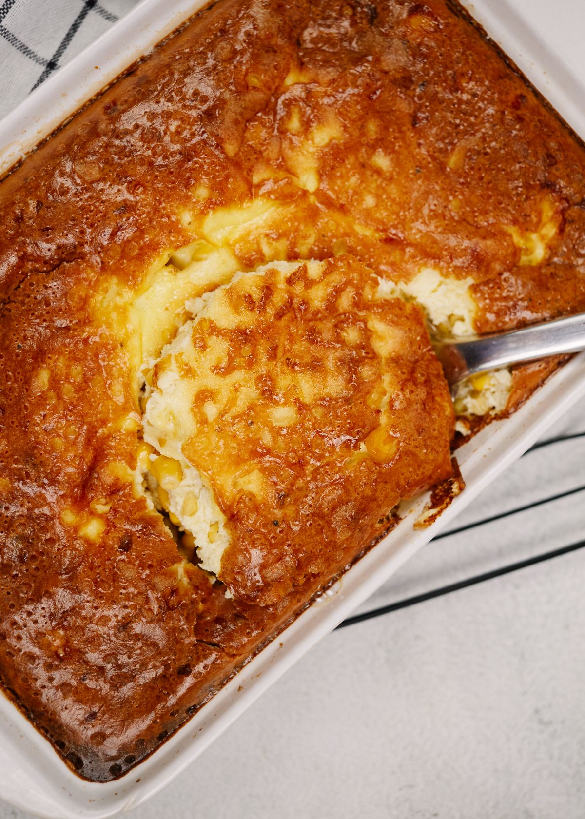 large baking dish of corn pudding with spoon in side