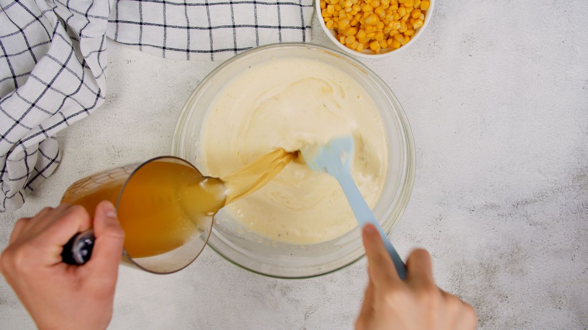 broth being stirred into large glass bowl of eggs