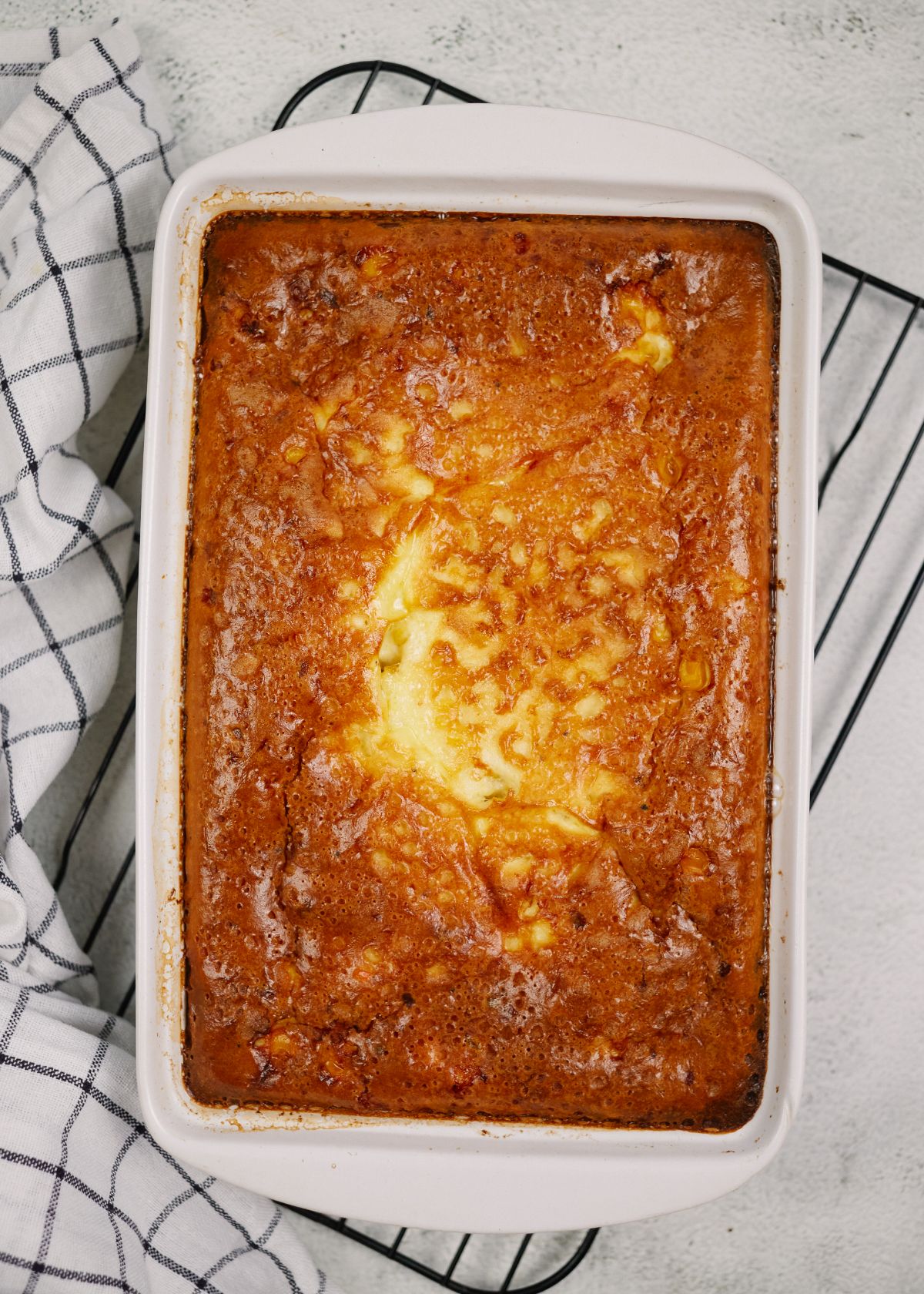 casserole dish of corn pudding laying on top of white and black striped napkin